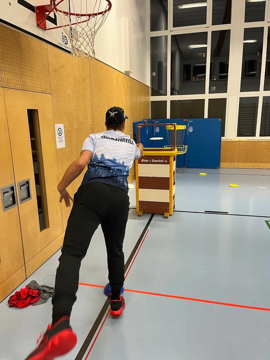 Spieler beim Wurf in der Sporthalle, im Hintergrund ein Korb