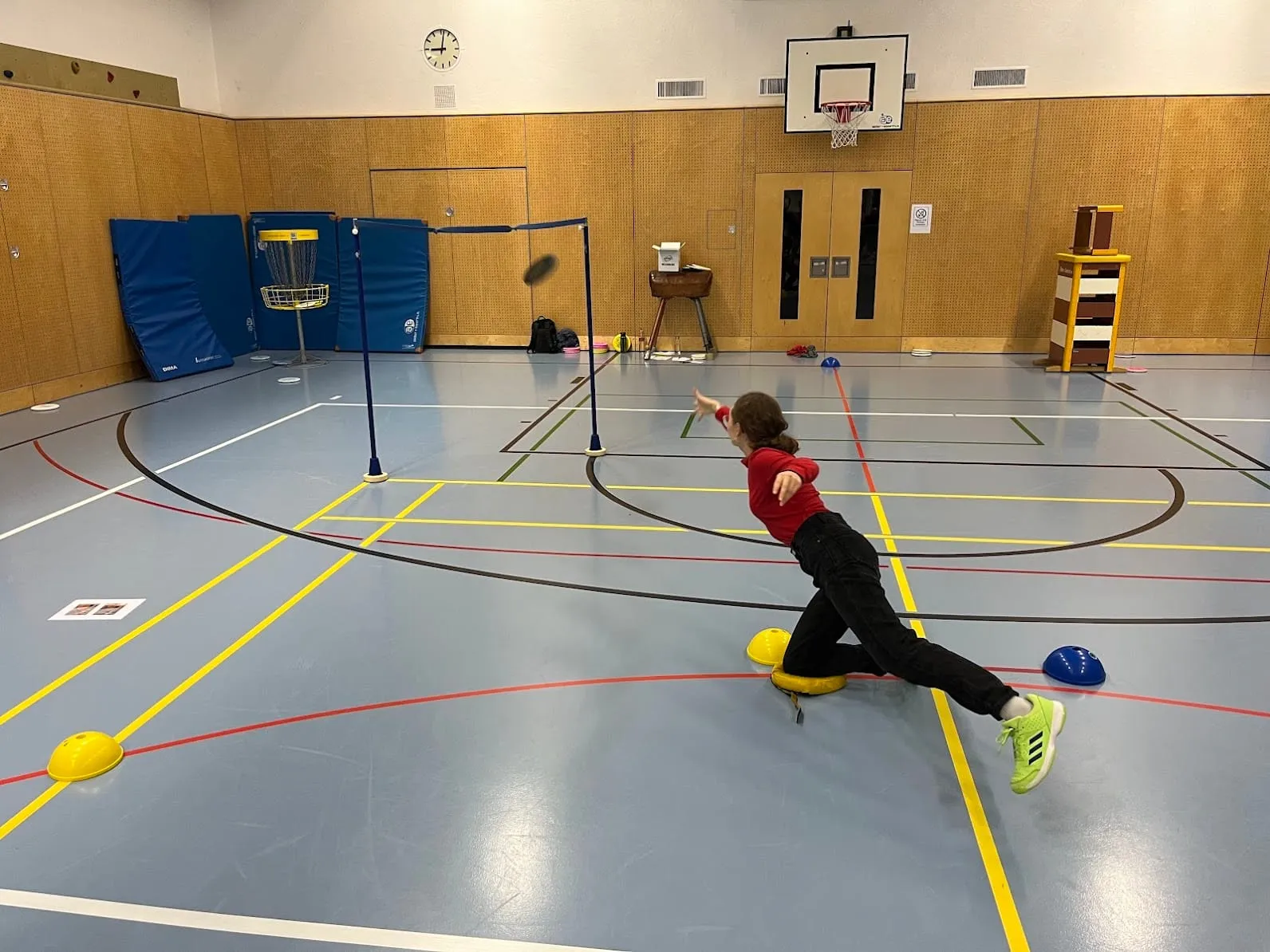Spielerin im Ausfallschritt beim Putten über Hindernisse in der Sporthalle