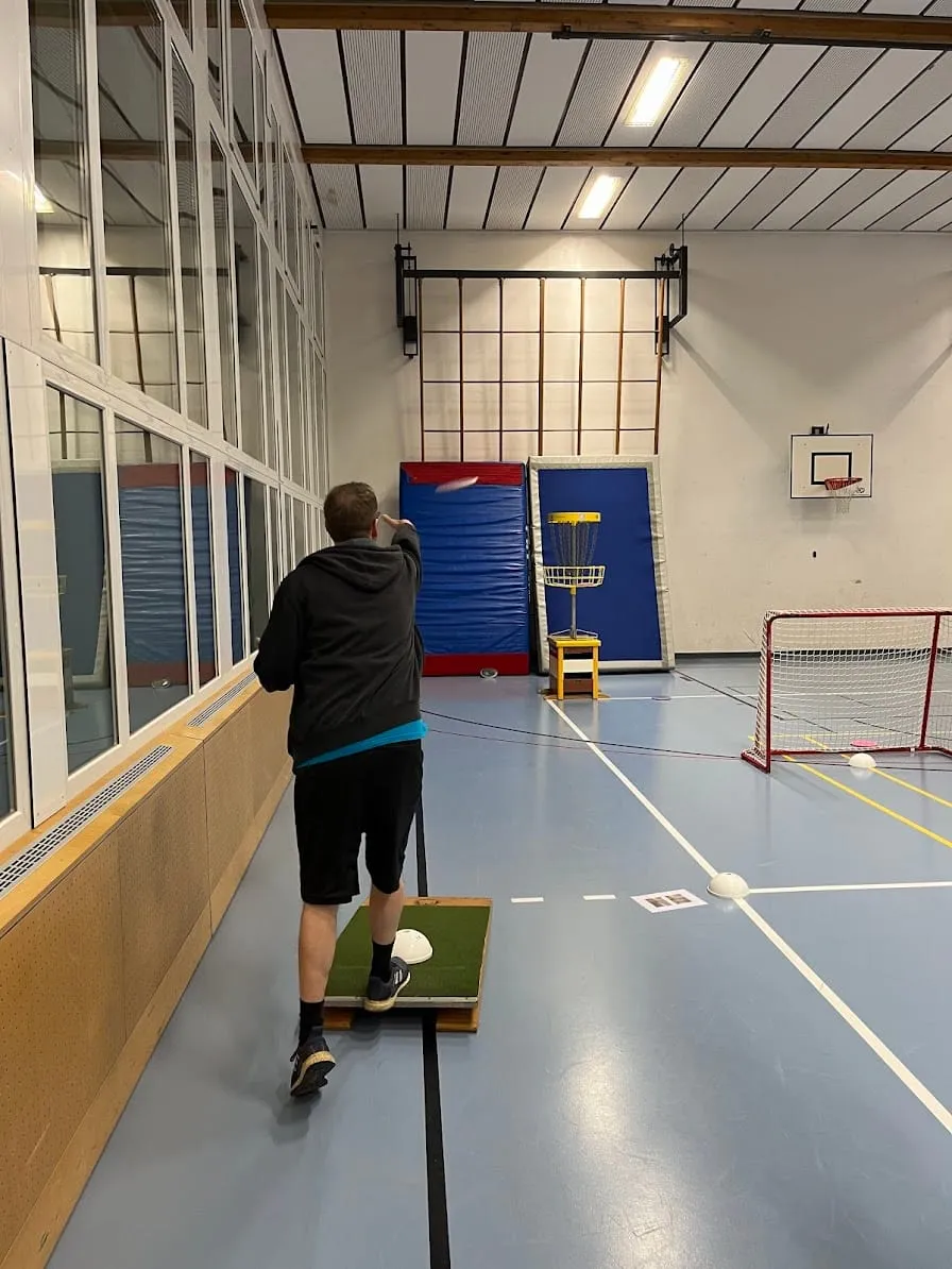 Spieler beim Putt von einer Matte in der Sporthalle