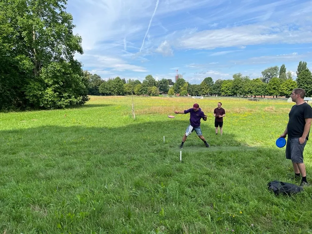 Training auf der weiten Wiese: ein Spieler wirft, zwei schauen zu