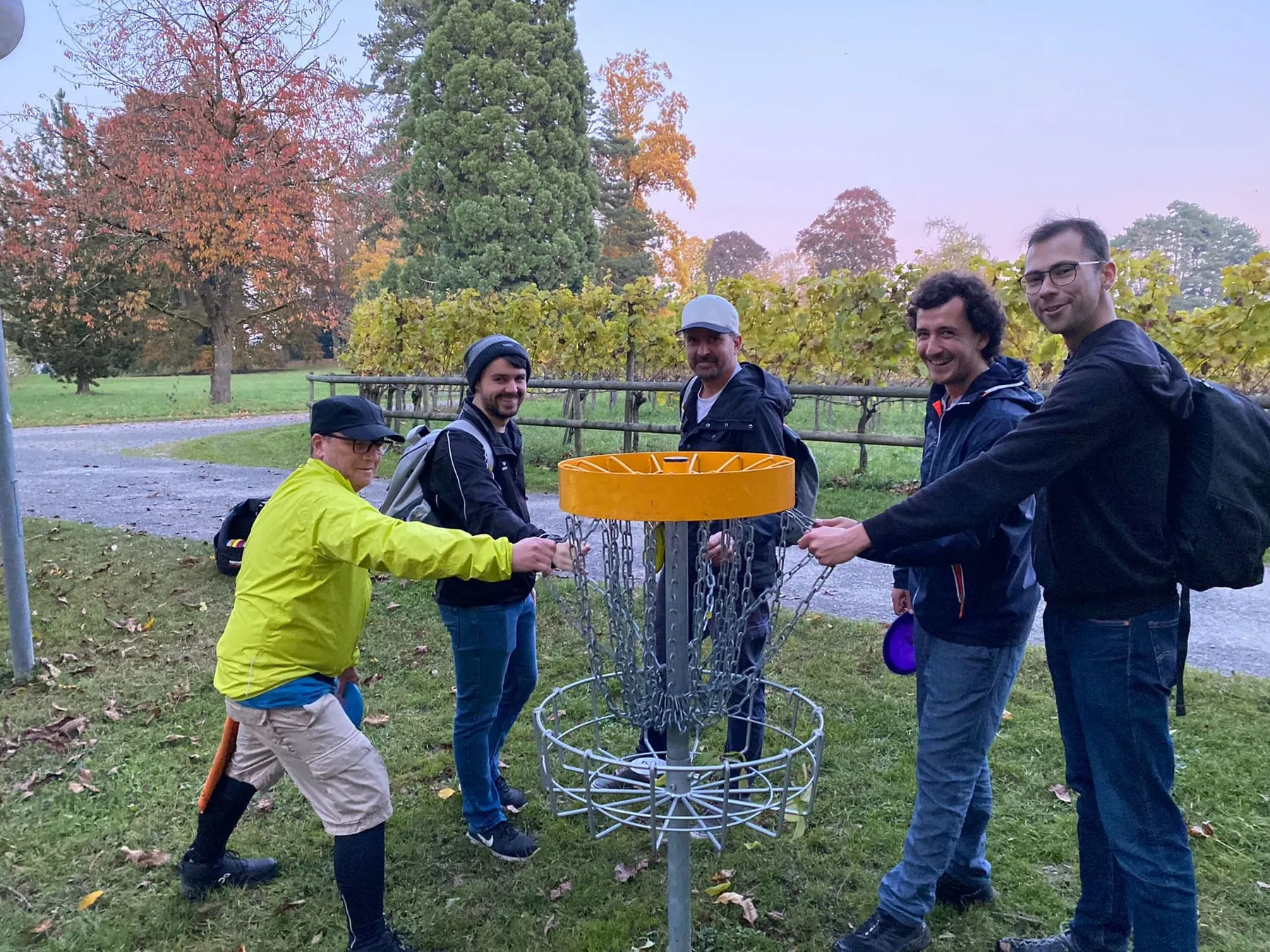 Vier Trainingsteilnehmer lachen in die Kamera am Disc Golf Korb
